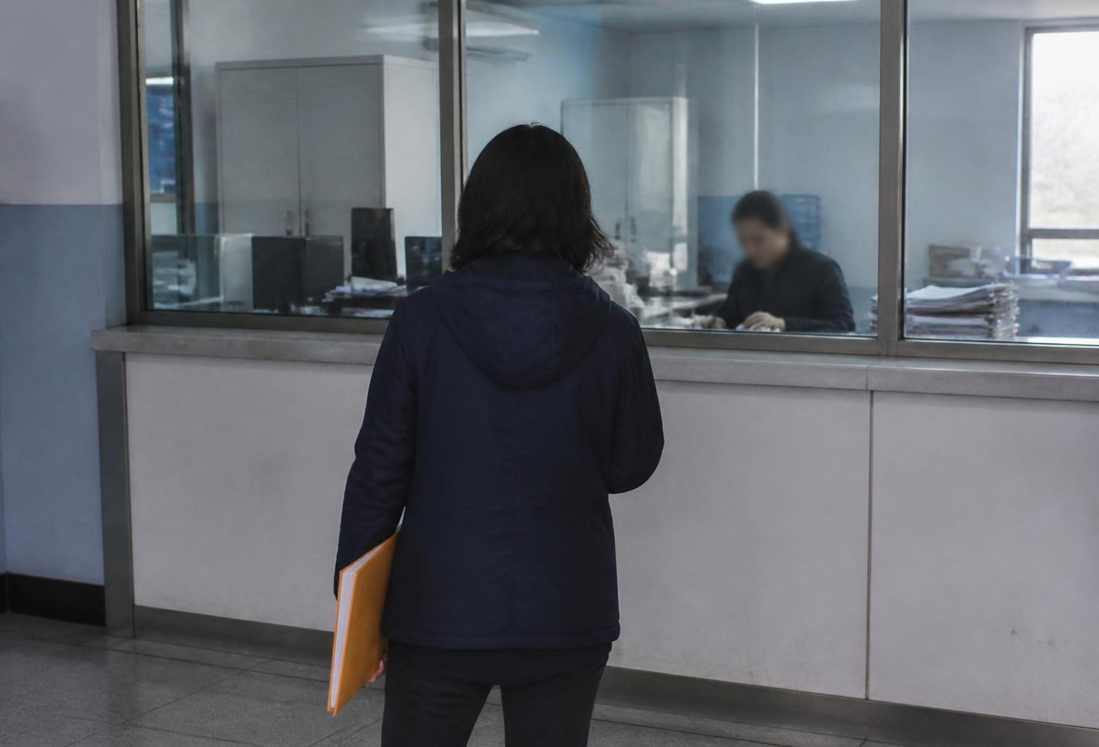 An applicant holding a folder at a government service counter window