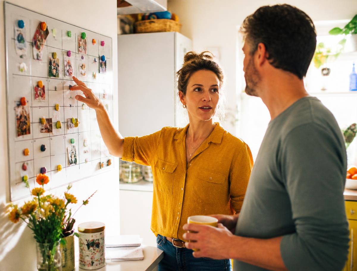 Two parents discussing a family calendar in a sunlit kitchen